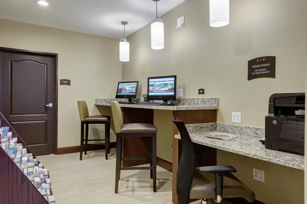 This inviting business center includes two computer stations on a granite countertop, a house phone, and a printer, set in a quiet, comfortable environment ideal for productivity and guest convenience.