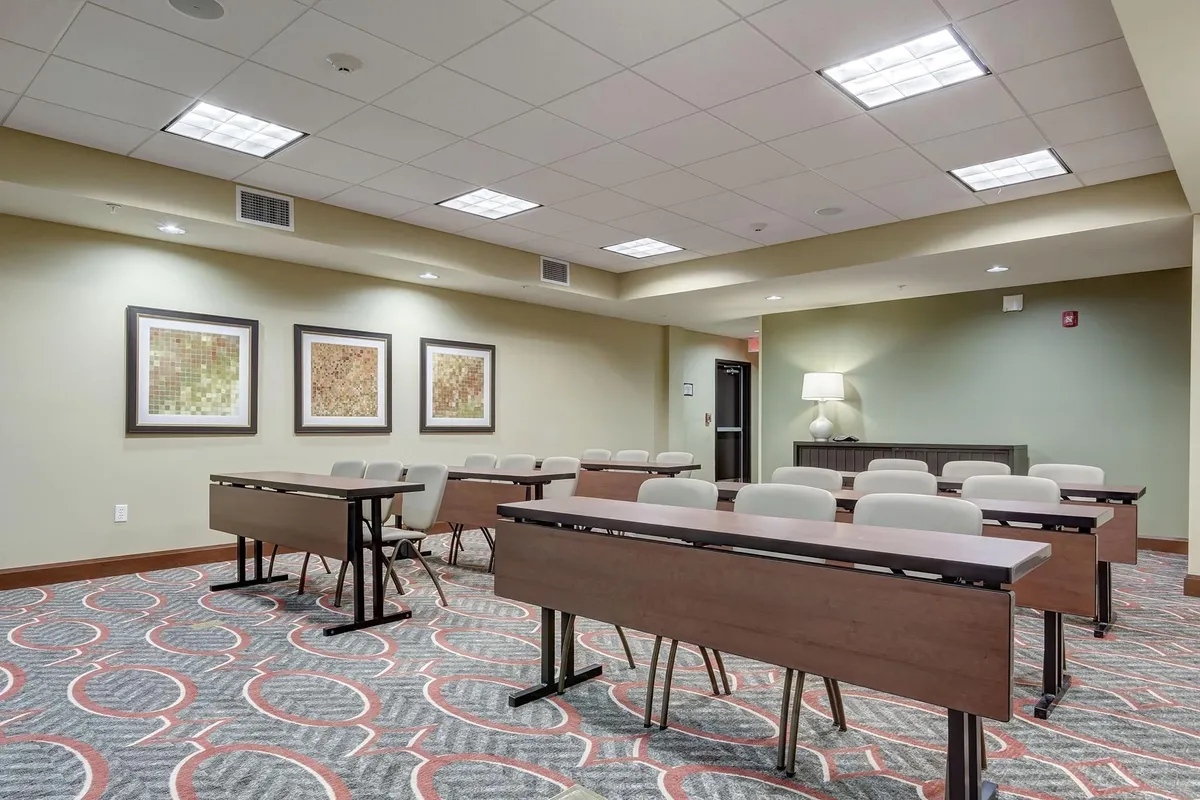 A tastefully arranged room with tables set up for meetings or work, complemented by framed artwork and a stylish lamp on a side table. The scene is both functional and inviting, offering a dedicated workspace within a thoughtfully decorated interior.