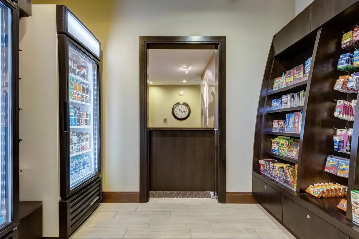 A cozy snack and drink nook featuring a refrigerated display, a variety of snacks, and a wall clock. The scene is casual and relaxed, ideal for families grabbing a quick bite or sharing treats after returning from local excursions.